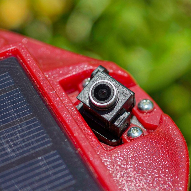 The camera lens module and feeder port in macro detail above the garden.
