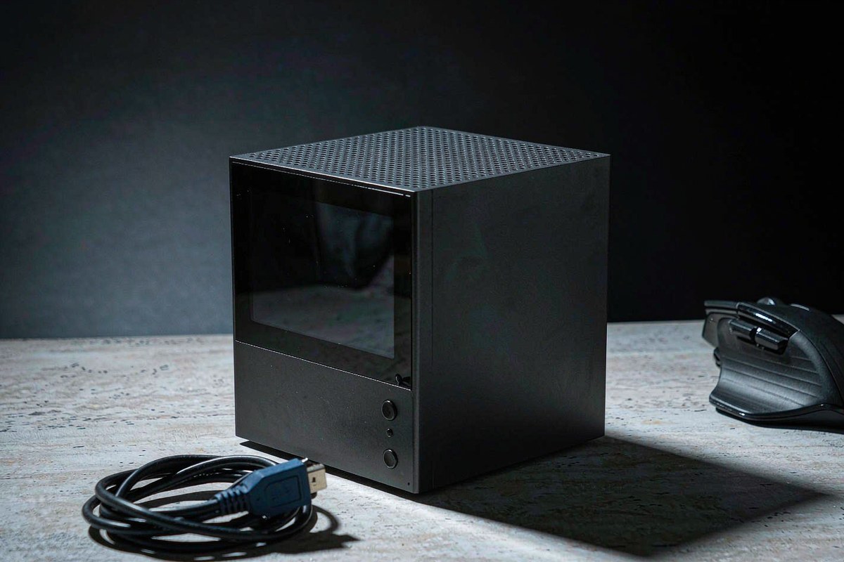 A small matte-black GMKtec G10 mini PC on a concrete desktop beside a coiled HDMI cable