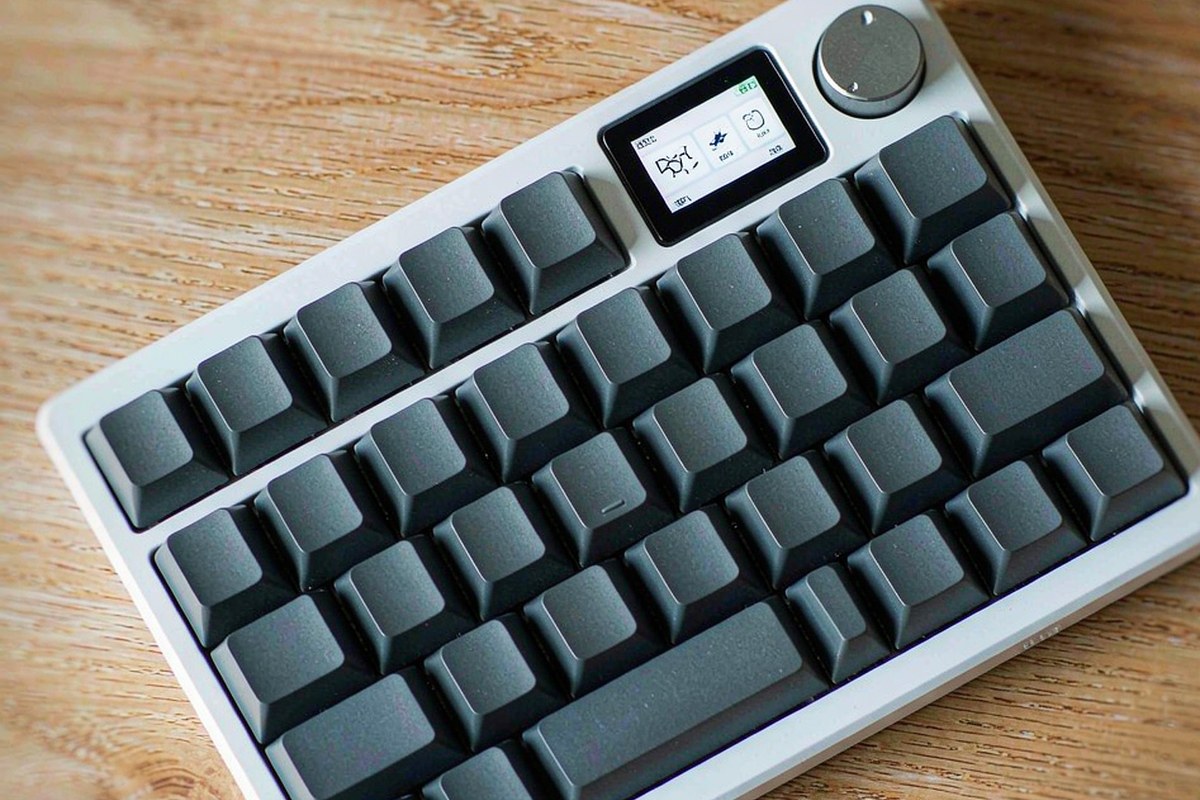 Overhead view of a compact 95 percent wireless mechanical keyboard with a screen and knob on a desk mat