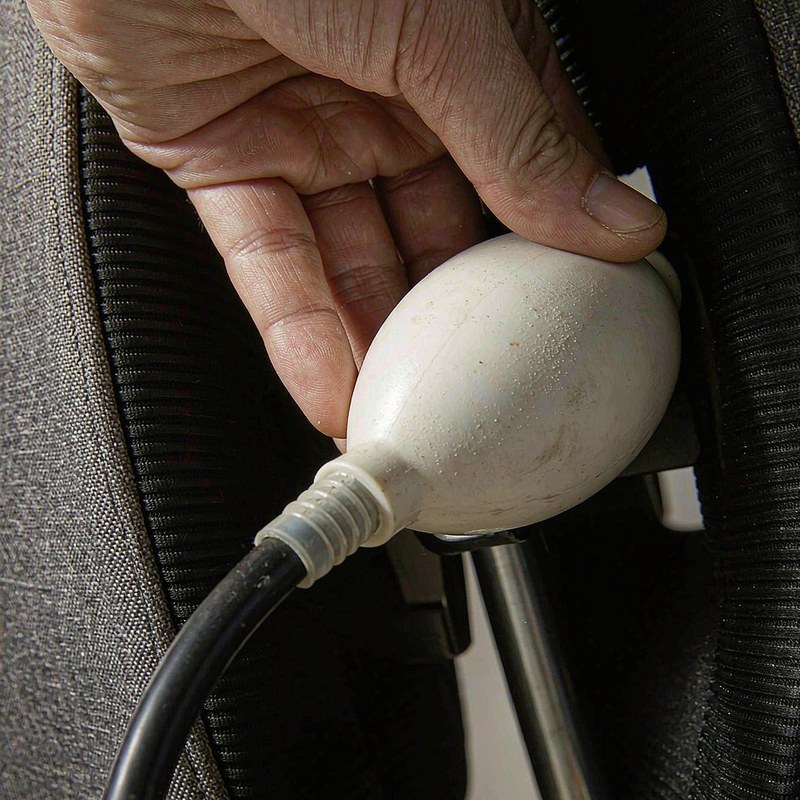 Macro view of a hand air pump bulb connected to the inflatable lumbar bladder of the chair.