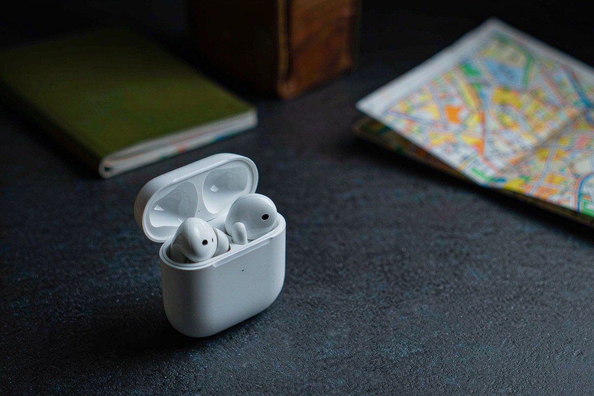 A pair of white Timekettle M3 translation earbuds in an open charging case beside a passport and a city map